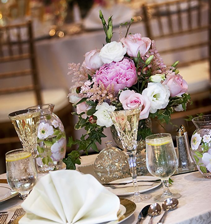 tables set for fine dining during a wedding event. Shallow depth of field, focus on the bouquet of flowers